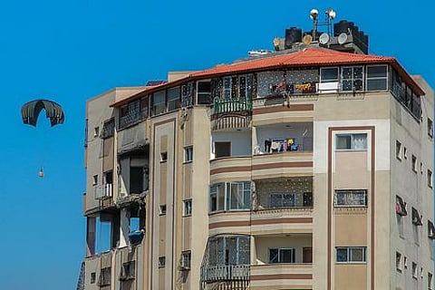 காஸா பகுதியில் விமானத்திலிருந்து வீசப்பட்ட உணவுப் பொருளுடன் குடியிருப்புக் கட்டடத்துக்கு அருகே வெள்ளிக்கிழமை இறங்கிய பாராசூட்.