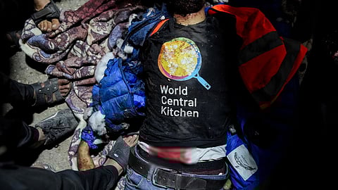 தெயிர்-அல்-பலா மருத்துவமனை பிரேத குவியலுக்கு மத்தியில் உயிரிழந்த நிலையில் மனிதநேய உதவிப் பணியாளர். அவரது டி-சர்டில் அமைப்பின் லச்சினை.