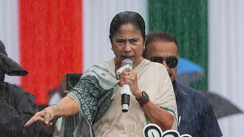 கொல்கத்தாவில் கொட்டும் மழையில் நனைந்தபடி பொதுக்கூட்டத்தில் பேசும் மம்தா பானர்ஜி