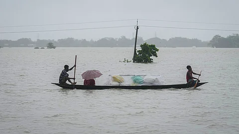 அஸ்ஸாம் வெள்ள நீரில் படகில் கடக்கும் மக்கள்