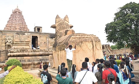 கங்கைகொண்டசோழபுரம் கோயிலுக்கு ஞாயிற்றுக்கிழமை வந்த அயலகத் தமிழ் இளைஞா்களுக்கு கோயில் வரலாறு குறித்து விளக்கம் அளிக்கும் அலுவலா்.