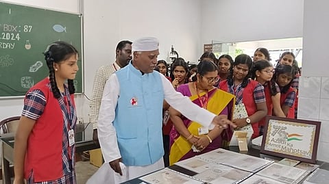 மாணவிகளுக்கு தபால்தலை குறித்து விளக்கமளித்த ஓய்வுபெற்ற அஞ்சல் துறை ராணுவ வீரா் சுந்தரம்.