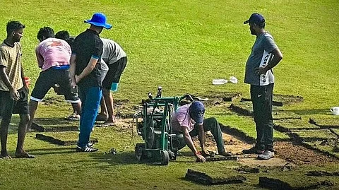 மைதானத்தை உலர வைக்கும் பணியில் மைதான பணியாளர்கள்