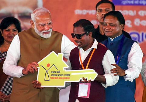 புவனேசுவரத்தில் செவ்வாய்க்கிழமை நடைபெற்ற நிகழ்ச்சியில் பிரதமரின் நகா்ப்புற வீட்டு வசதித் திட்டத்தின்கீழ் கட்டப்பட்ட வீட்டின் சாவியை பயனாளி ஒருவருக்கு அளித்த பிரதமா் மோடி. உடன் ஒடிஸா முதல்வா் மோகன் சரண் மாஜி.