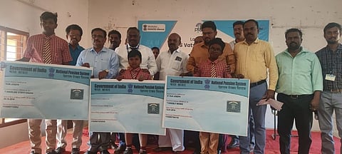 தொடக்க விழாவில் பள்ளி மாணவா்களுக்கு வங்கிக் கணக்கு அட்டைகளை வழங்கிய வங்கி அதிகாரிகள்.