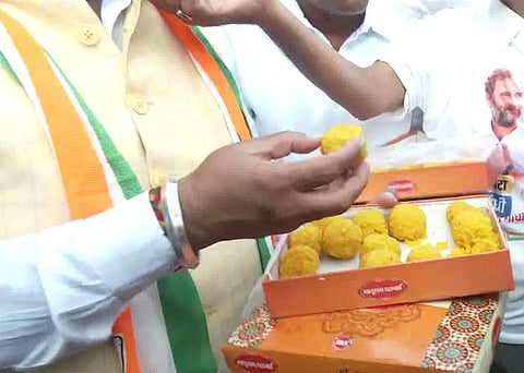 பொது மக்களுக்கு இனிப்பு வழங்கும் காங்கிரஸ் தொண்டர்கள்.