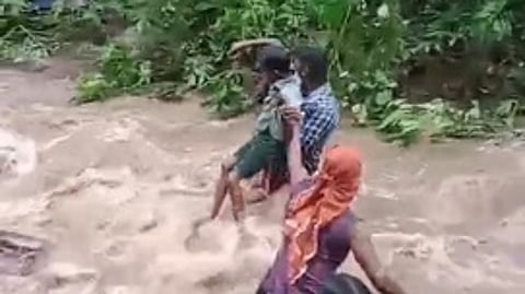 பேச்சிப்பாறை அருகே மோதிரமலை- கொழிஞ்சிமடம் பாதையில் பெருக்கெடுத்துப் பாய்ந்த வெள்ளத்தைக் கடக்கும் பள்ளிக் குழந்தைகள்.