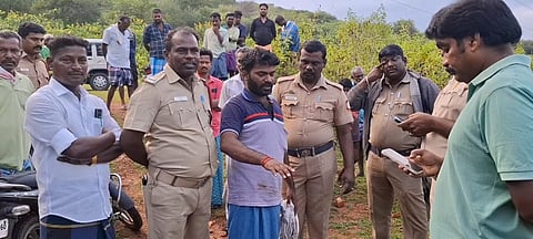 நத்தம் அருகே இலவச வீடு கேட்டு உயர் மின் கோபுரத்தில் ஏறி நின்று போராடிய இளைஞரிடம் விசாரணை செய்யும் காவல்துறையினர்.