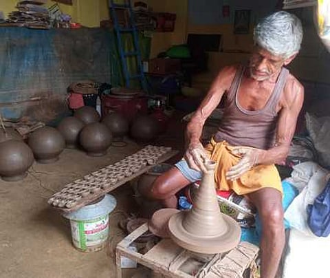காவிலிபாளையத்தில் அகல் விளக்கு  தயாரிக்கும்  பணியில் திங்கள்கிழமை  ஈடுபட்டுள்ள  மண்பாண்டத்  தொழிலாளி.