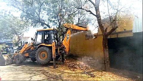 பொக்லைன் இயந்திரத்தால் சுவரை இடிக்கும் பணியில் ஈடுபட்ட தீயணைப்புத் துறையினா்