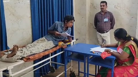 மதுரையில் உதவியாளர் உதவியுடன் பிளஸ் 1 பொதுத் தோ்வு எழுதிவரும் மாணவன் தினேஷ்.