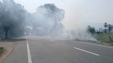 குப்பைகளுக்கு தீ வைத்ததில் எழும்பிய புகையைக் கடந்து செல்லும் வாகனங்கள்