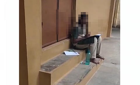 வகுப்பறையின் வாசற்படியில் அமர்ந்து தேர்வெழுதும் மாணவி.