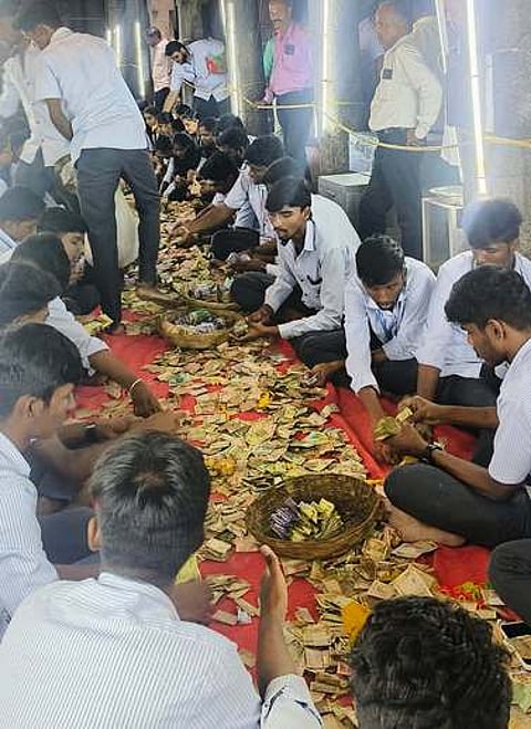 உண்டியல் காணிக்கையை எண்ணும் பணியில் ஈடுபட்டுள்ள அதியமான் கல்லூரி மாணவா்கள்