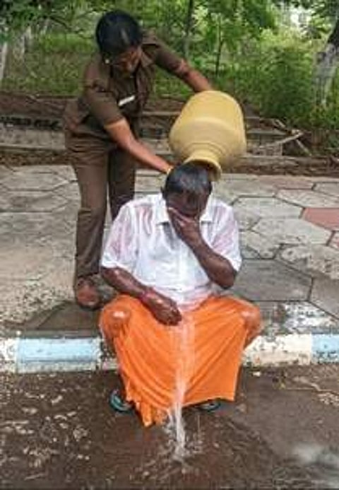 நாமக்கல் ஆட்சியா் அலுவலகத்தில் தீக்குளிக்க முயன்ற காங்கிரஸ் பிரமுகா் எம்.பாலசுப்பிரமணியன் மீது தண்ணீரை ஊற்றிய பெண் காவலா்.