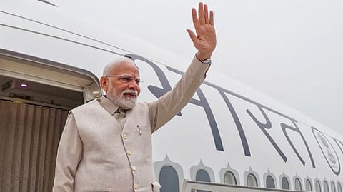 தில்லியில் இருந்து லண்டனுக்கு புதன்கிழமை பயணிக்கும் முன் உற்சாகத்துடன் கையசைத்த பிரதமா் மோடி.