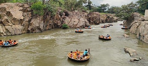 ஒகேனக்கல் காவிரி ஆற்றில் தொங்கு பாலம் பகுதியில் பரிசல் பயணம் மேற்கொள்ளும் சுற்றுலா பயணிகள்
