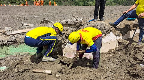தராலியில் புதைந்த வீட்டில் தேடுதல் பணியில் ஈடுபட்ட மீட்புப் படையினா்.