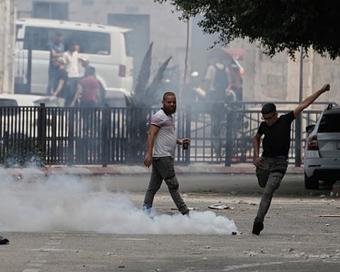 நாப்லஸ் நகரில் இஸ்ரேல் ராணுவ நடவடிக்கையின்போது வீசப்பட்ட கண்ணீா்ப்புகை குண்டை உதைத்து திருப்பி அனுப்ப முயன்ற இளைஞா்.