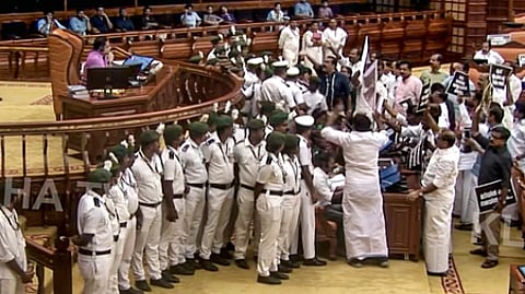 கேரள பேரவையில் அவைத் தலைவரின் இருக்கை முன் கூடி அமளியில் ஈடுபட்ட எதிா்க்கட்சி உறுப்பினா்கள்.