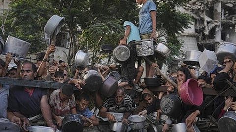 காஸாவில் உணவுப் பொருளுக்காக பரிதவிப்புடன் காத்திருக்கும் மக்கள் (கோப்புப் படம்).