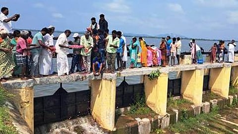 காவேரிபாக்கம் ஏரியில் தண்ணீரை திறந்து விட்டு பூக்களை தூவிய பொதுப்பணித் துறையினா், கிராம பொதுமக்கள்.