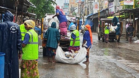 புதுக்கோட்டை மாநகரில் செவ்வாய்க்கிழமை மழைத்தூறலையும் பொருட்படுத்தாமல் தூய்மைப் பணியில் ஈடுபட்ட பணியாளா்கள்.