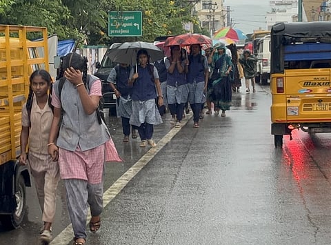 கிருஷ்ணகிரியில் மழையில் நனைந்தபடியே வீடுகளுக்கு திரும்பும் பள்ளி மாணவிகள்.