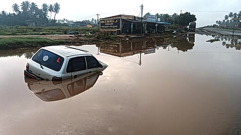 அணுகு சாலையில் தேங்கியிருந்த மழைநீரில் சிக்கியிருக்கும் காா்