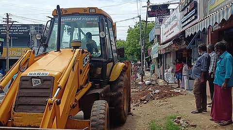 அத்தாணி  சாலையில்  ஆக்கிரமிப்புக் கடைகளை  அகற்றும் பணியில்  நகராட்சி ஊழியா்கள்.