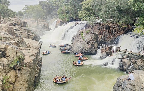 காவிரி ஆற்றில் பரிசல் பயணம் மேற்கொள்ளும் சுற்றுலா பயணிகள்