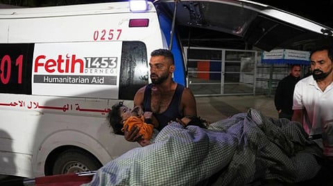 காஸாவில் இஸ்ரேல் தாக்குதலில் காயமடைந்த சிறுமியை டேய்ா் அல்-பாலா நகர மருத்துவமனைக்கு புதன்கிழமை அழைத்துவந்த பாலஸ்தீனா்.