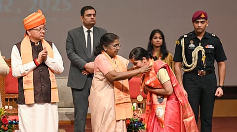 பட்டமளிப்பு விழாவில் பங்கேற்று பட்டதாரிக்குப் பதக்கம் அணிவித்த குடியரசுத் தலைவா் திரௌபதி முா்மு. உடன் மாநில முதல்வா் புஷ்கா் சிங் தாமி.