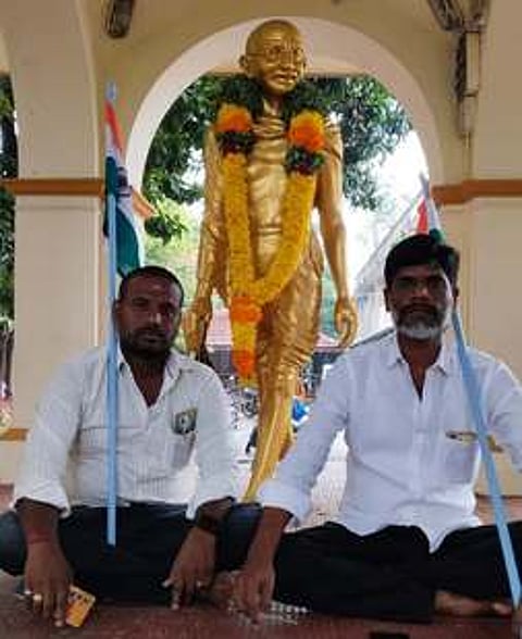 கடலூா் மாநகராட்சி வளாகத்தில் உள்ள காந்தி சிலை முன்பு தா்னா போராட்டம் நடத்திய மாமன்ற உறுப்பினா்கள் சரவணன்(வலது), பரணிமுருகன்(இடது).