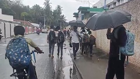 மழையில் நனைந்தப்படி செல்லும் மாணவர்கள்