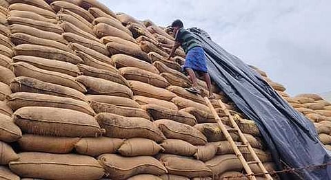 சேதமடைந்த நெல் மூட்டைகளை சுத்தம் செய்யும் பணியில் ஈடுபட்ட ஊழியா்.