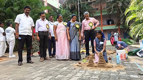 மாநில அளவிலான கலைத் திருவிழாவில் மாணவி உருவாக்கிய மணல் சிற்பத்தை பாா்வையிடும் முதன்மைக் கல்வி அலுவலா் மகேஸ்வரி.
