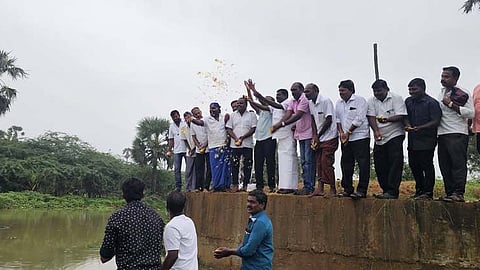 தொட்டியான்குளம் மறுகாலில் மலா் தூவிய பொ. சிவபத்மநாதன் உள்ளிட்டோா்.