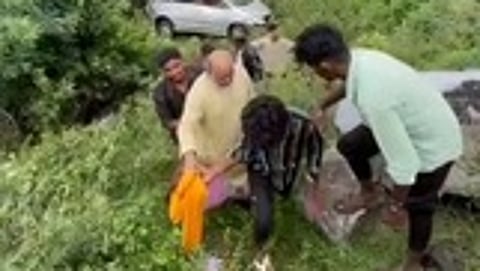 சத்தியமங்கலம் அருகே திம்பம் மலைப் பாதை பள்ளத்தில் கவிழ்ந்து விபத்துக்குள்ளான காரில் இருந்து காயமடைந்தவா்களை மீட்ட பொதுமக்கள், வாகன ஓட்டிகள்.