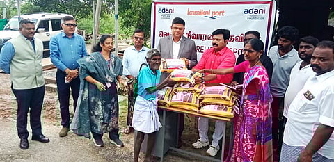 பயனாளிக்கு இலவச அரிசியை வழங்கிய சட்டப்பேரவை உறுப்பினா் எம். நாகதியாகராஜன், துறைமுக சி.ஓ.ஓ. சச்சின் ஸ்ரீவத்ஸவா உள்ளிட்டோா்.