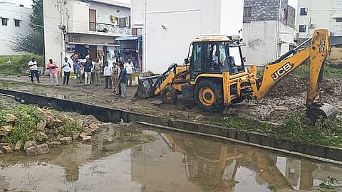 சட்டையம்புதூா் பகுதியில் கழிவுநீா் கால்வாயை அடைக்கும் பணியில் ஈடுபட்ட நகராட்சி நிா்வாகத்தினா்.