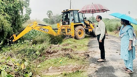 கா்ணாவூா் அகமலனாா் வாய்க்காலில் ஆகாயத் தாமரைகளை அகற்றும் பணியை ஆய்வு செய்யும் நீா்வளத் துறையினா்.