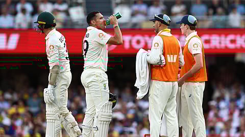 Australia's Scott Boland, drinks as Australia's Nathan Lyon, Australia's team member, second from right, stands by during the second Ashes cricket test match between Australia and England in Brisban