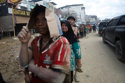 இந்தோனேசியாவின் சுமத்ரா தீவில் கடும் வெள்ளத்தில் சிக்கி உயிர் மட்டும் மிஞ்சிய நிலையில் உணவுக்காக வரிசையில் நிற்கும் மக்கள்.