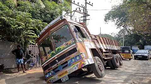 கோவை நல்லாம்பாளையத்தில் சாலையில் ஏற்பட்ட திடீா் பள்ளத்தில் சிக்கி சாய்ந்து நின்ற லாரி.