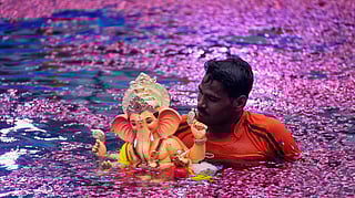 மும்பையில் விநாயகர் சதுர்த்தி கொண்டாட்டத்தின்போது, விநாயகர் சிலையை குளத்தில் பக்தர் கரைக்கிறார்.