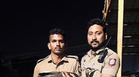 காயமடைந்த நிலையில் மீட்கப்பட்ட மயிலுடன் காவலா் யுவராஜ் (வலது புறம்)