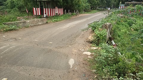 தடுப்புச் சுவா் சேதமாகி பள்ளமாக காட்சியளிக்கும் சாலை.