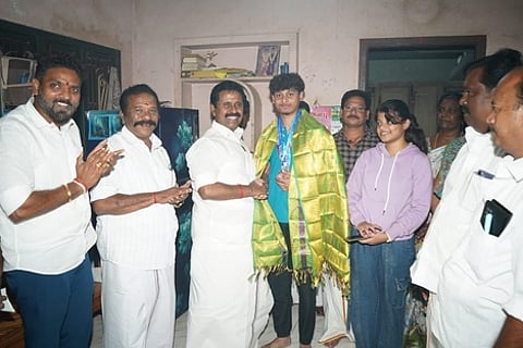 சேங்காலிபுரத்தில் பதக்கம் வென்ற இளைஞருக்கு சால்வை அணிவித்து பாராட்டுத் தெரிவிக்கும் முன்னாள் அமைச்சா் ஆா். காமராஜ்.