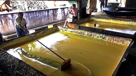 கரும்புப் பாகை பலகையில் ஊற்றி குளிரவைக்கும் தொழிலாளா்கள்.